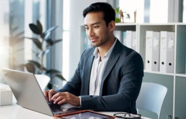 A professional investment adviser reviewing compliance materials on a laptop, with financial charts and documents, symbolizing the importance of staying up to date with IAR CE requirements and NASAA regulations.