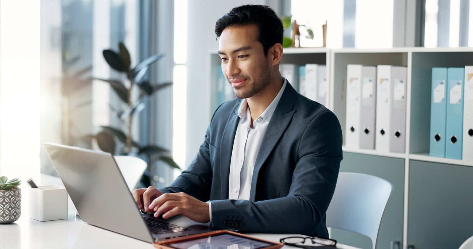 A professional investment adviser reviewing compliance materials on a laptop, with financial charts and documents, symbolizing the importance of staying up to date with IAR CE requirements and NASAA regulations.